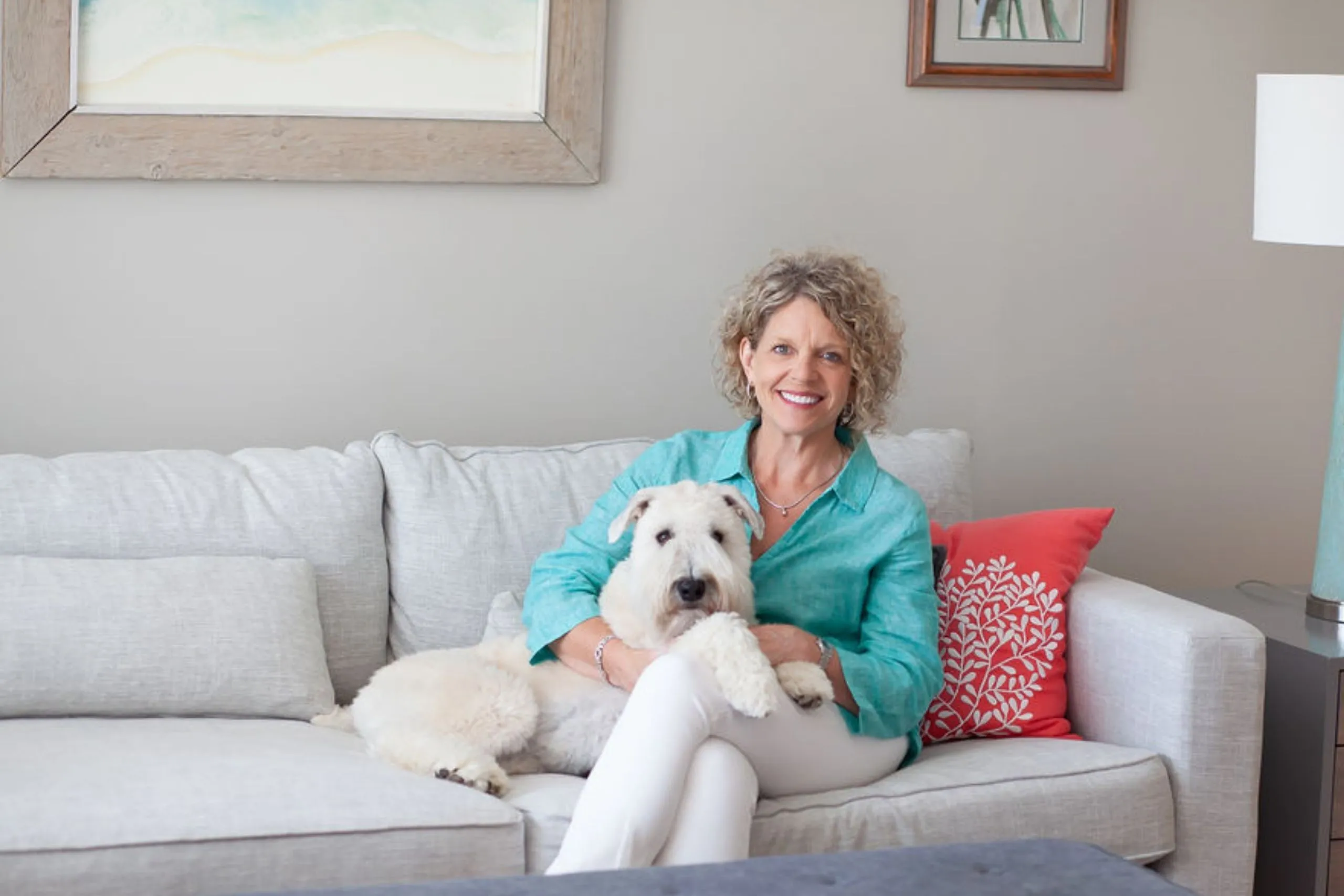 Rhonda sitting on a couch with her white dog